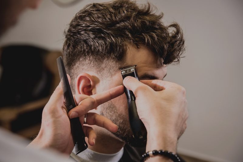 Barber carefully trimming a customer’s hair with clippers