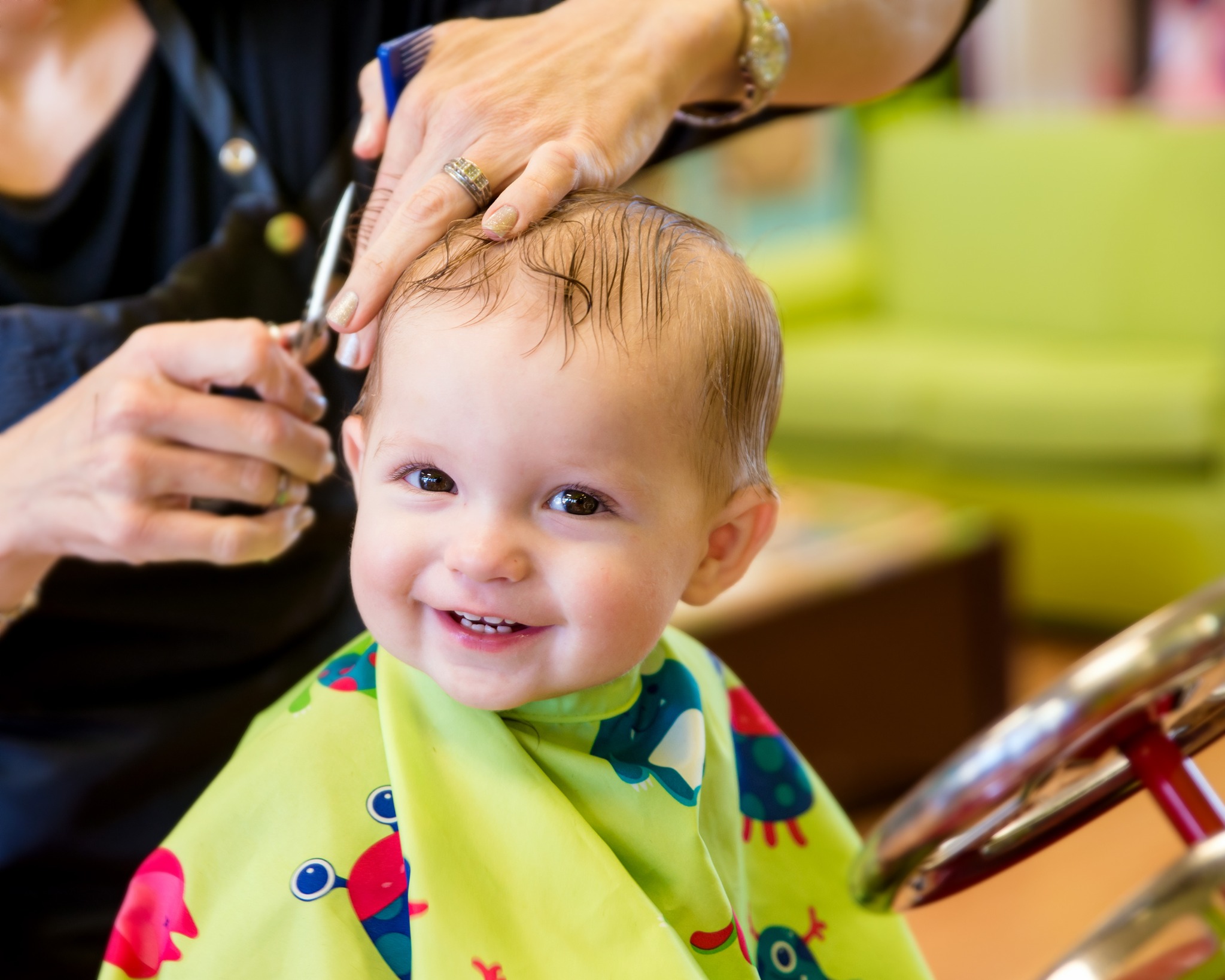Smiling young child receiving a first haircut