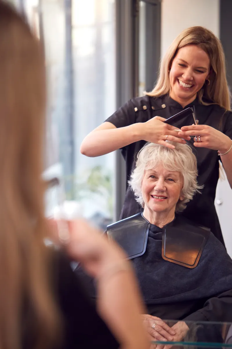 Hair professional styling an older customer’s hair